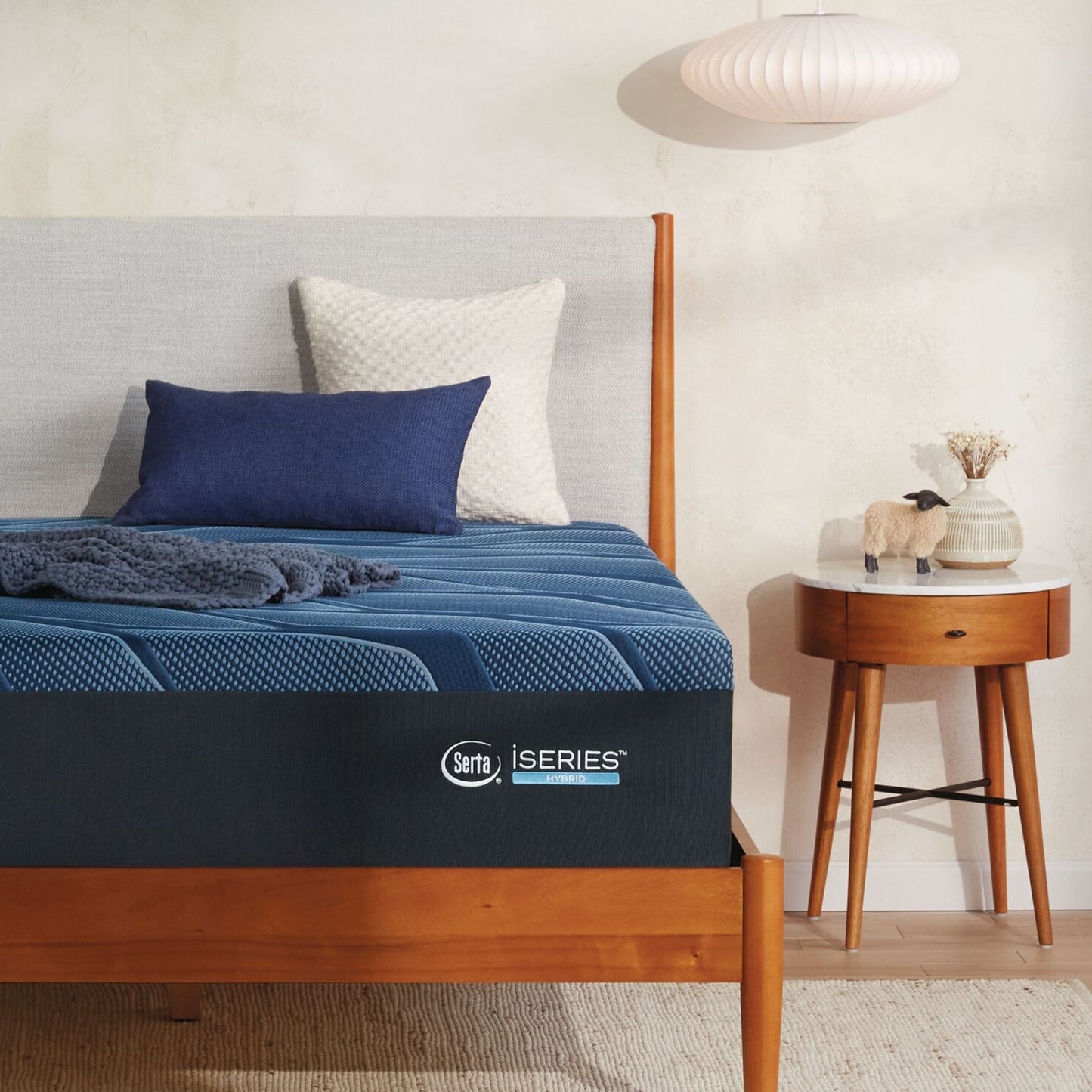 A wooden bed with a Serta iSeries medium blue mattress, blue and beige pillows||feel: medium||level: Ultimate