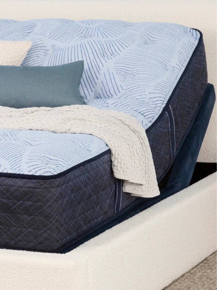 Close up view of a Serta mattress on an adjustable bed frame with the head of the bed propped up. 