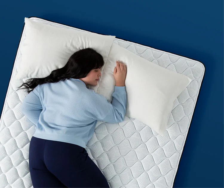 Woman sleeping on her stomach on a firm Serta mattress, demonstrating extra support needed for stomach sleepers.