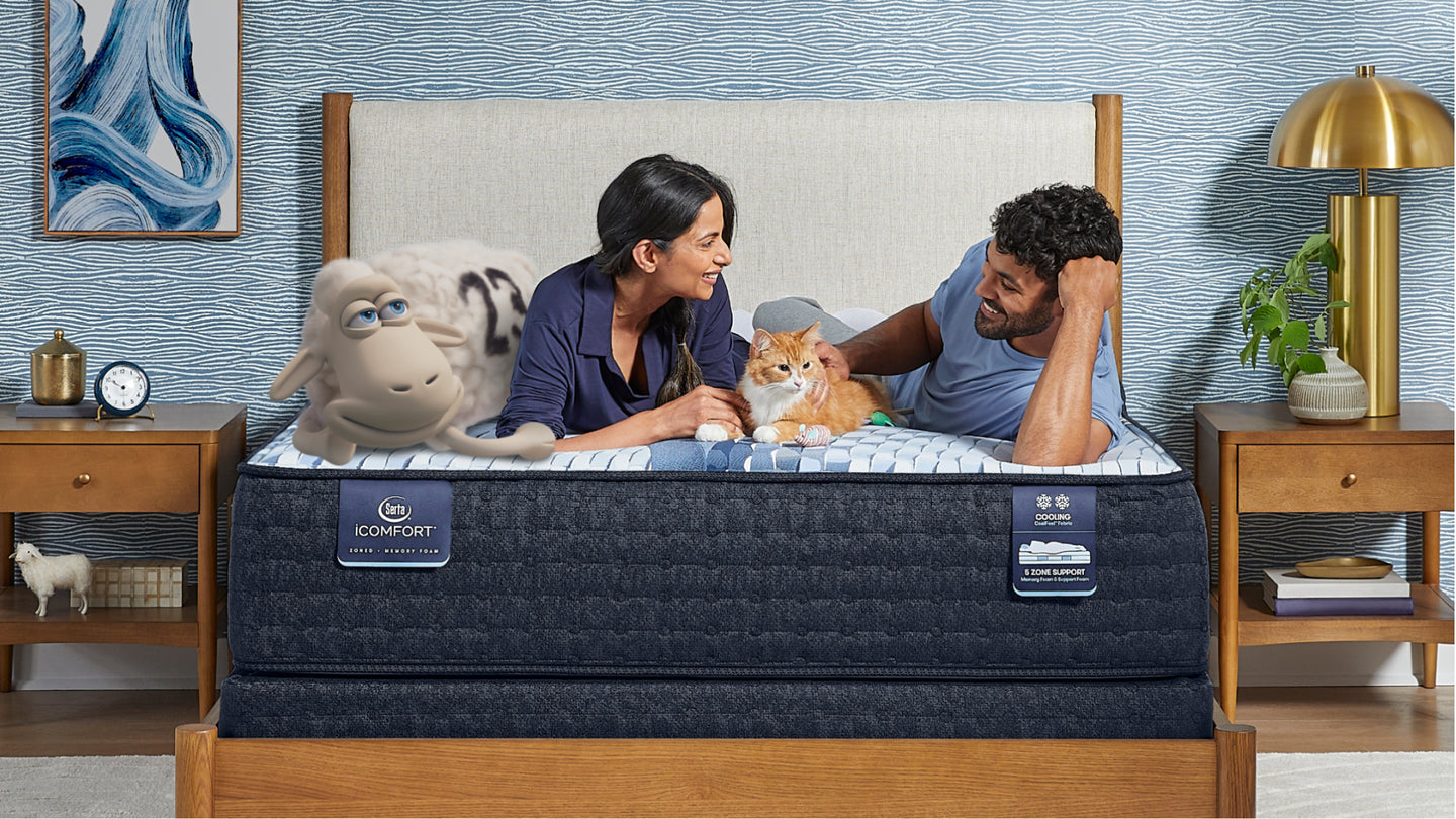 Serta sheep, woman, orange cat and man laying on a Serta iComfort mattress smiling at each other